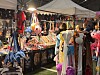 Innendørs messestand med fargerike leker, suvenirer og flere besøkende som ser på varene.