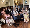 Stor familie samlet i en stue med sofaer og lenestoler for å feire en 100-årsdag.