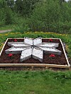 Stjerneformet blomsterbed i en grønn park med gress og busker i bakgrunnen.